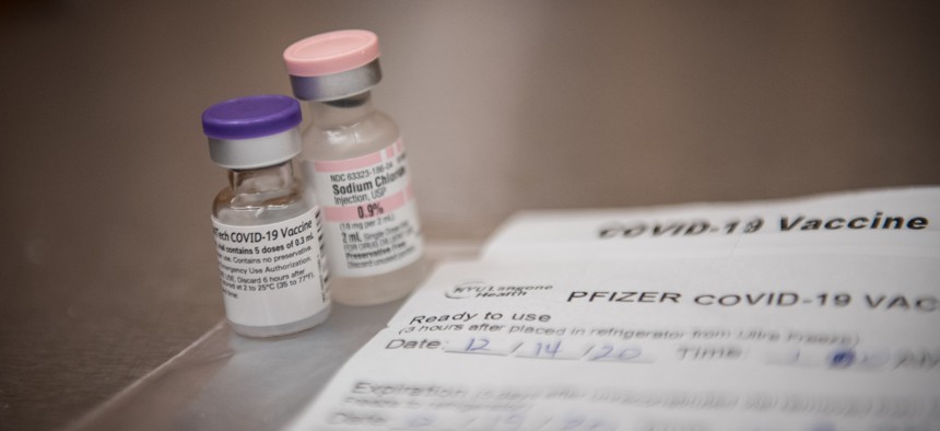 A COVID-19 vaccine dose and paperwork for the Pfizer vaccine.