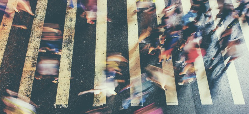 A busy crosswalk with lots of blurry people.