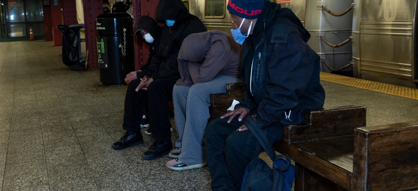 Men with face masks sit in New York City subway station.