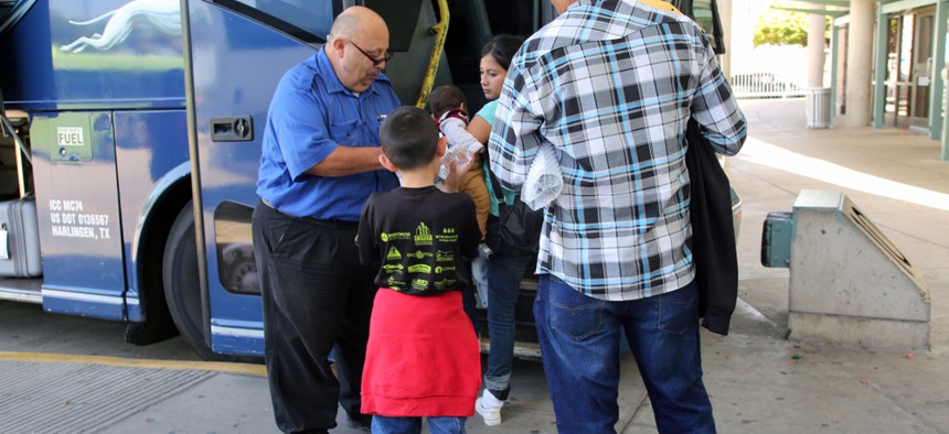 A bus driver takes tickets in 2017 from a group of Central American refugees going to stay with U.S. family while awaiting their Immigration Court hearings.