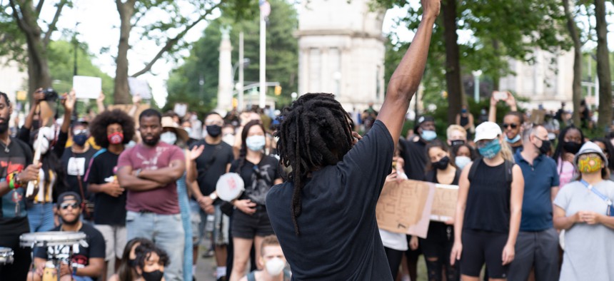 Man raises fist in air during protest for racial justice in New York City.