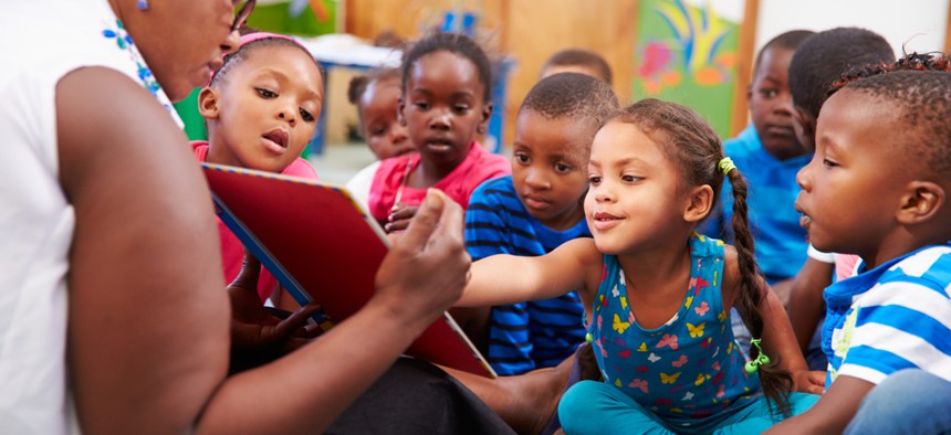 A stock image of an adult reading to a group of young children.