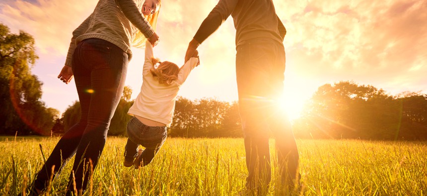 Two parents with a child at sunset