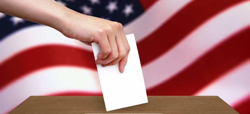 A photo of someone casting a ballot with an American flag in the background.