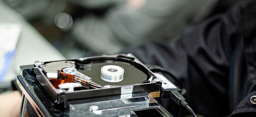 Dismantled hard drive sits in front of person