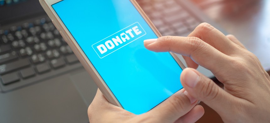 Person holding phone, which has a screen prompting the person to donate.