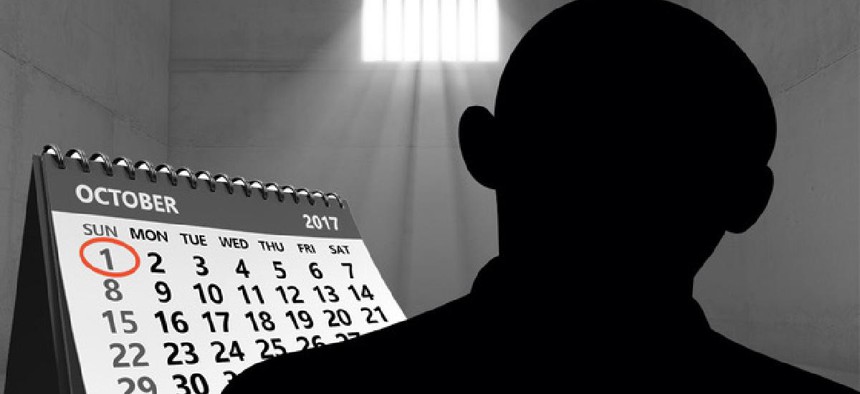 A shadowed figure in a darkened room with barred windows  alongside a calendar with the date Oct. 1 circled