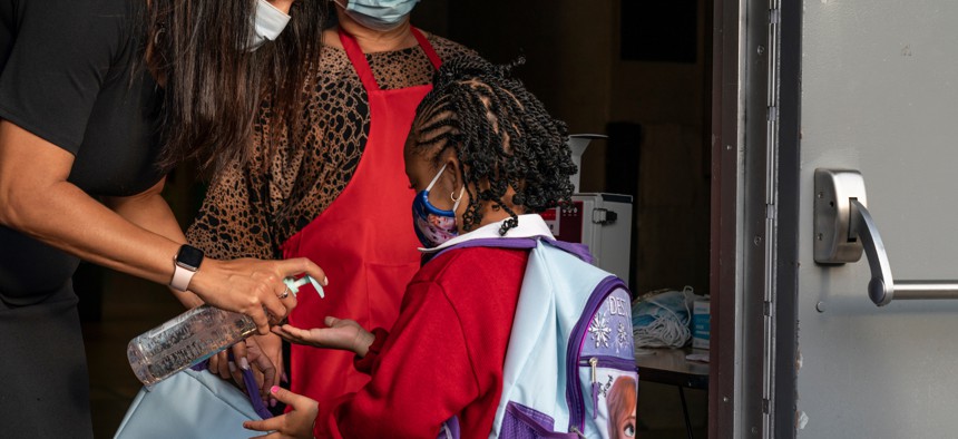 Teacher gives student hand sanitizer.