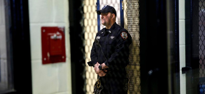Guard standing against a wall in Rikers.