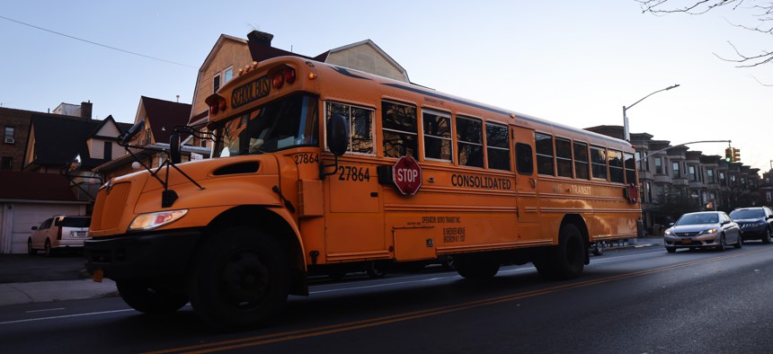 A public school bus driving down a street in Brooklyn.