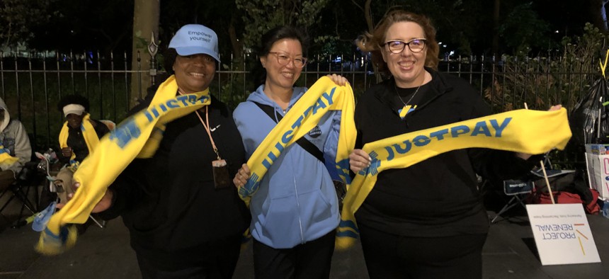 Nadine Akinyemi and Esther Lok of Bridging Access to Care and Michelle Jackson of the Human Services Council rally outside City Hall on Wednesday night.
