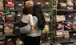 A migrant mother and her child pick through baby clothes at Little Shop of Kindness on Manhattan’s Upper East Side. 