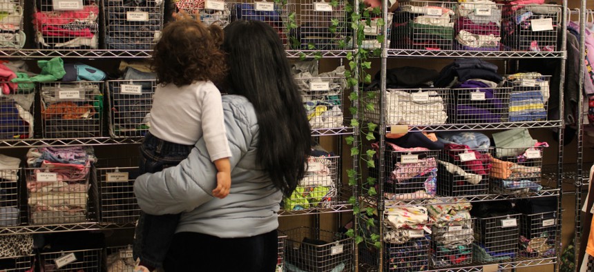 A migrant mother and her child pick through baby clothes at Little Shop of Kindness on Manhattan’s Upper East Side. 