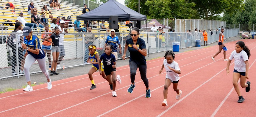 Young NYRR participants on the track and field with New York City Police Department First Deputy Commissioner Tania Kinsella.